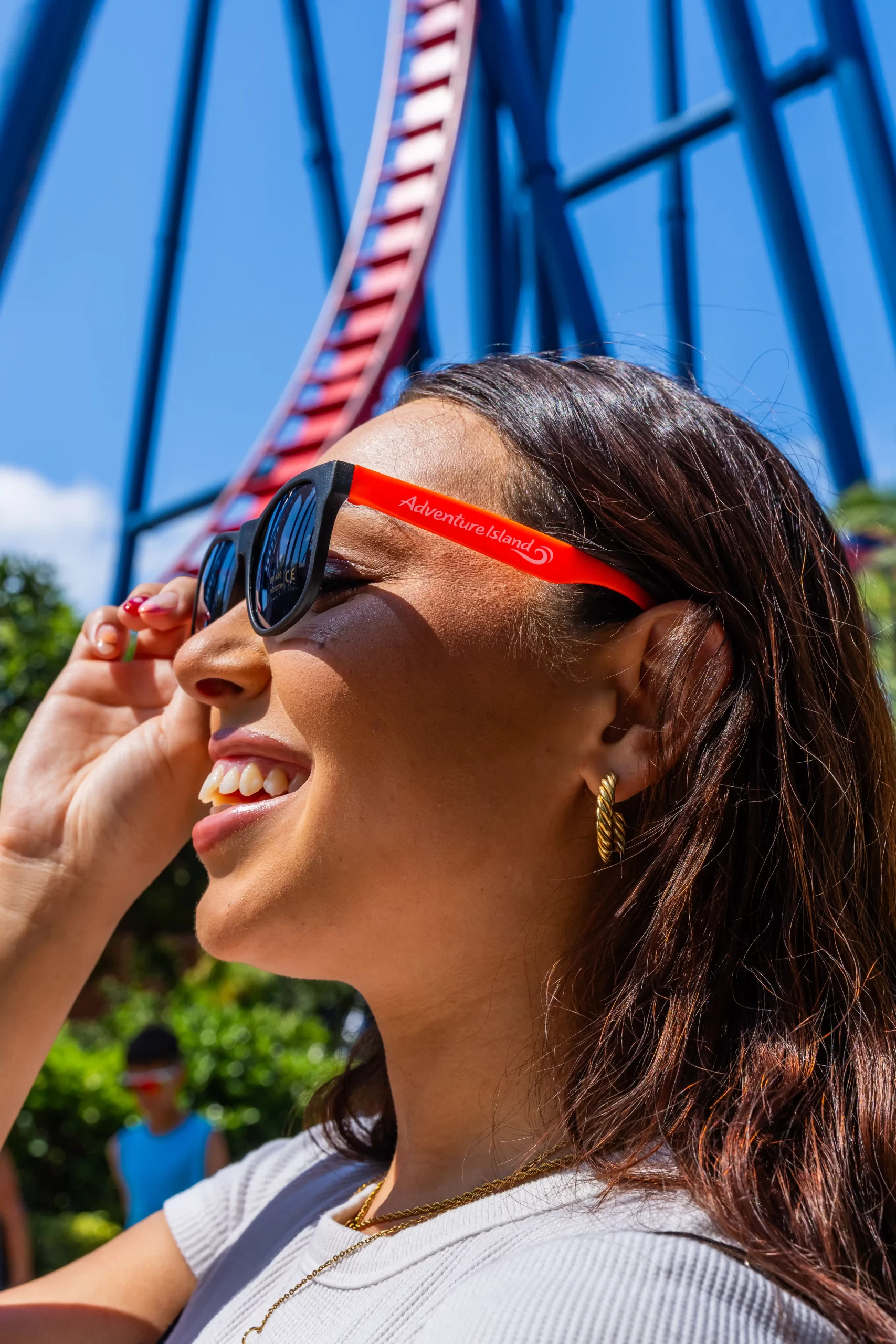A guest putting on branded sunglasses with red arms at the park