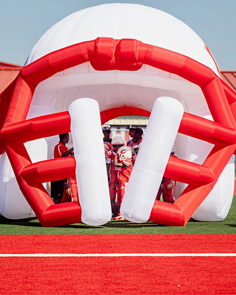 Young football players gathered inside a giant red and white inflatable helmet before running onto the field