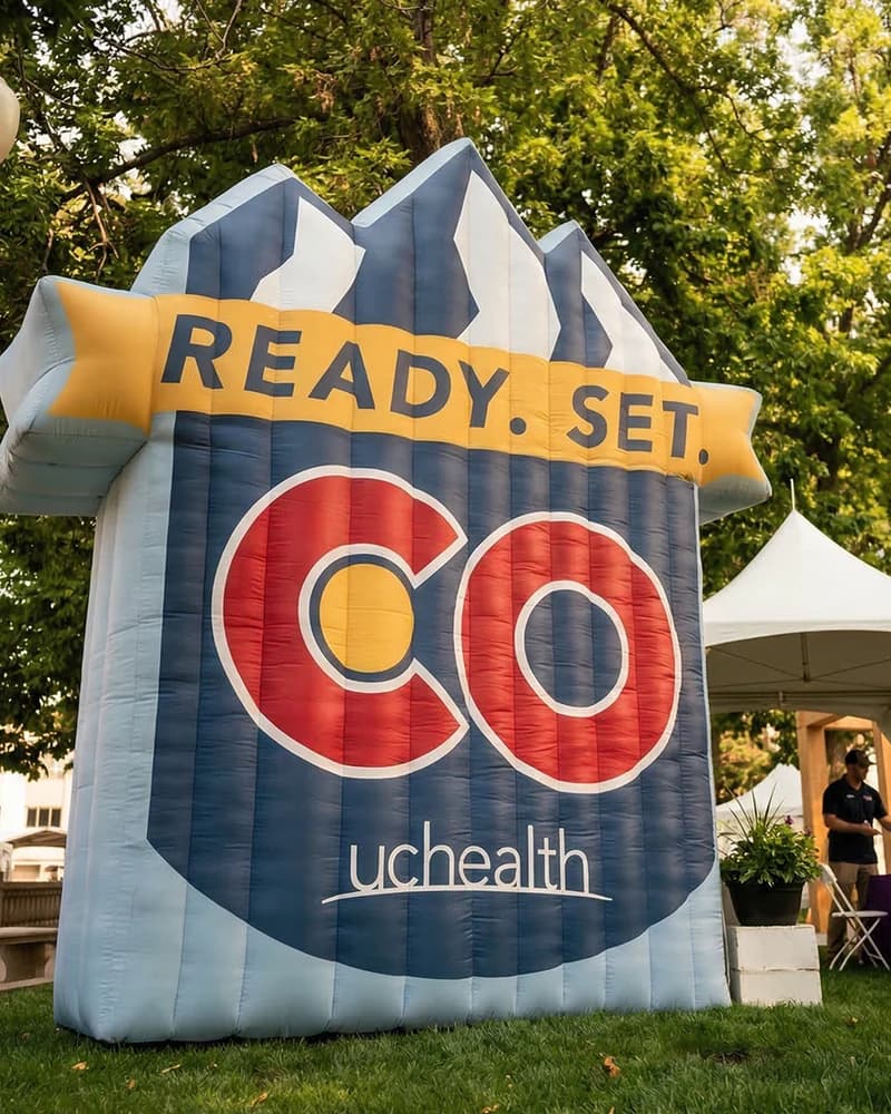 A giant inflatable in the shape of a company's mountain logo, standing on the grass at an outdoor event