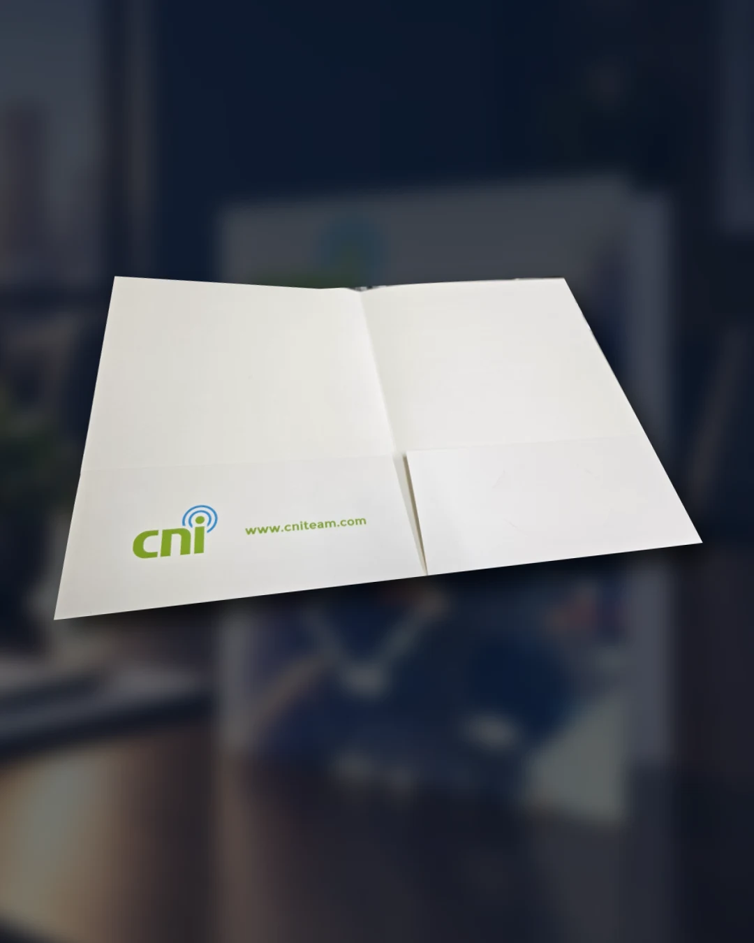 Cinematic artwork incorporating the actual customer-supplied photo of an open CNI presentation folder, with two pockets and business-card slits in the right pocket