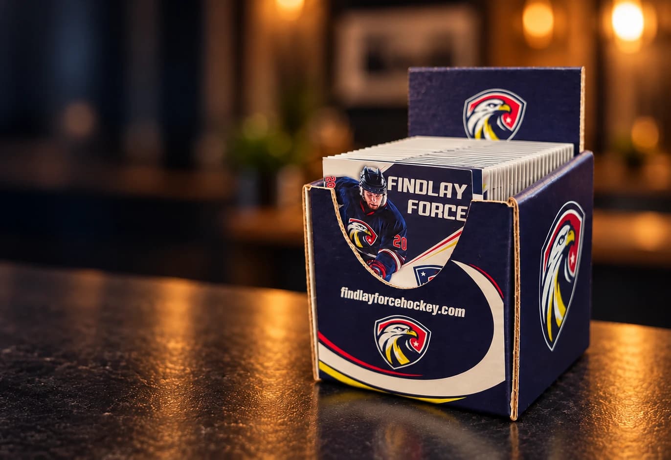 Cinematic artwork, based on photos of the actual product, of a navy Findlay Force countertop display full of folded pocket schedules on a warmly lit counter