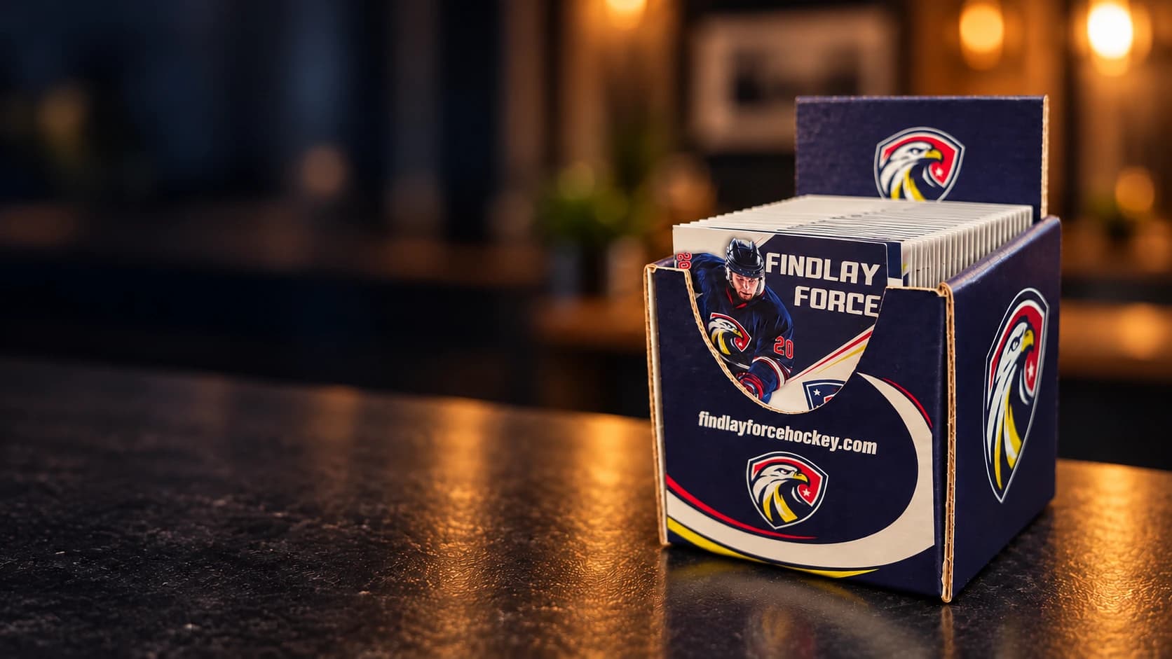 Cinematic artwork, based on photos of the actual product, of a navy Findlay Force countertop display full of folded pocket schedules on a warmly lit counter