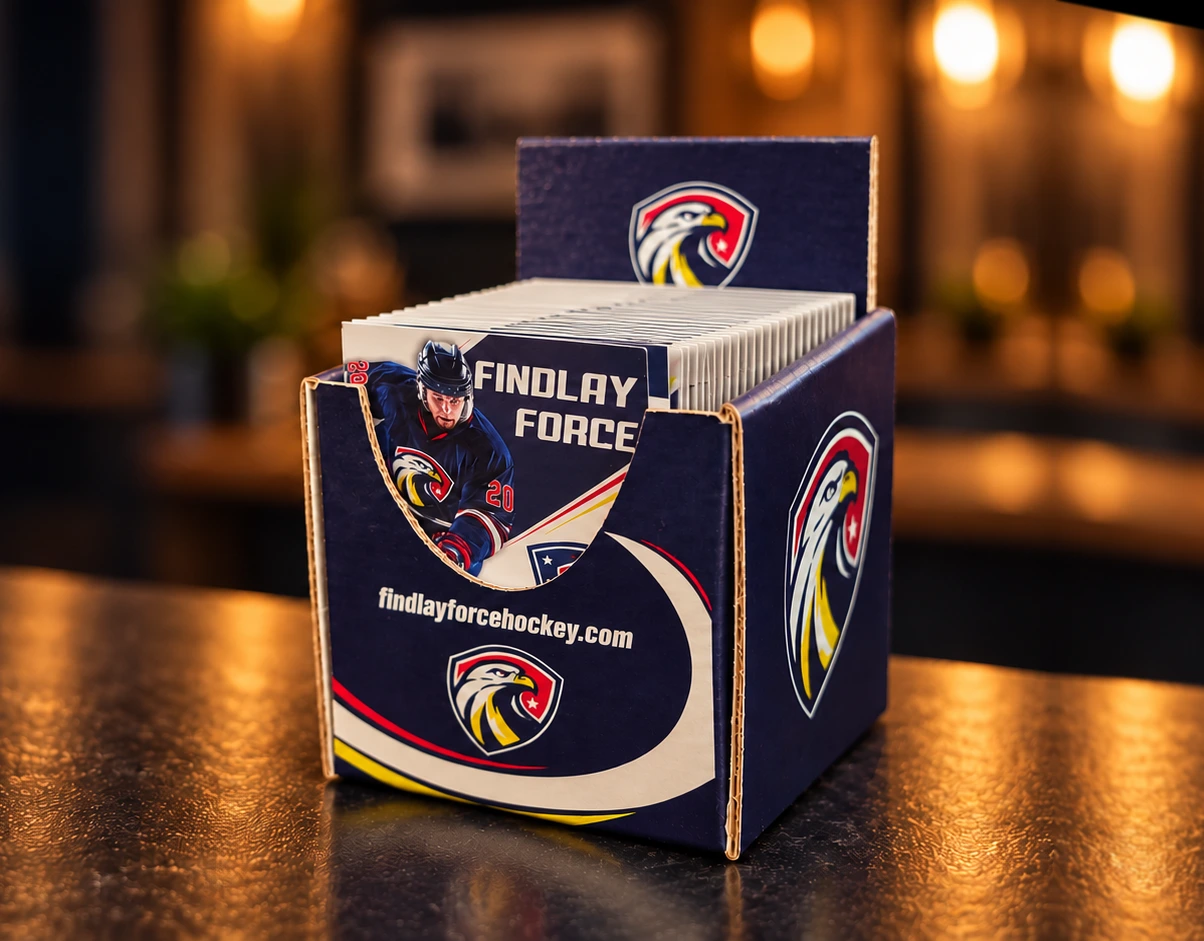 Cinematic artwork, based on photos of the actual product, of a navy Findlay Force countertop display full of folded pocket schedules on a warmly lit counter