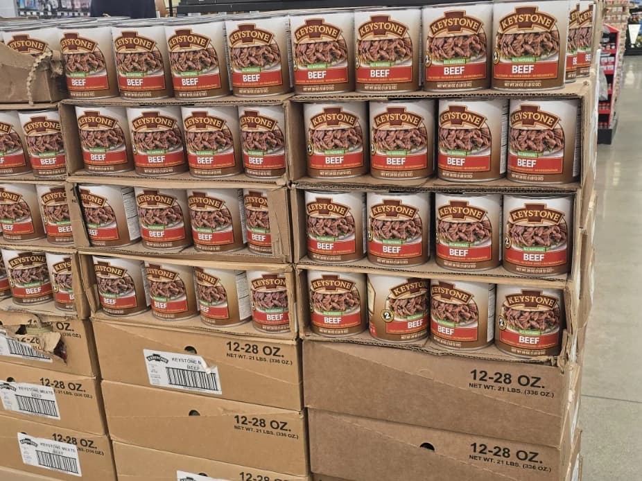 A pallet display of Keystone canned beef, with trays of labeled cans stacked above their shipping cases