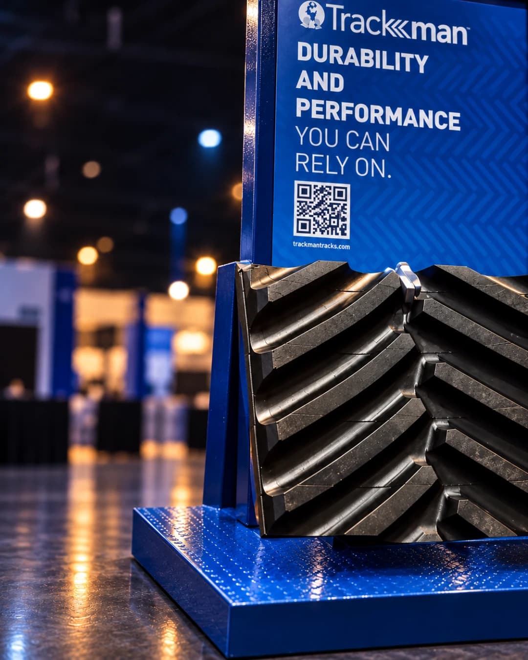 Cinematic close view of one stand: the blue powder coated frame, the printed panel, and a section of black rubber track resting on the base
